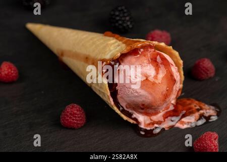 ice cream with red raspberry berries and fresh jam on a black board, berry flavored ice cream with fresh raspberries and blackberries Stock Photo
