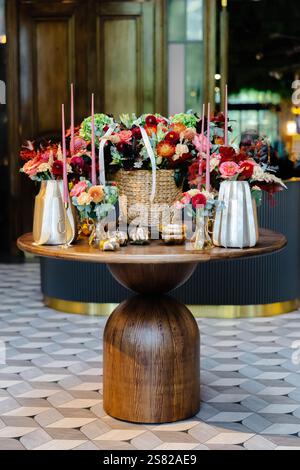 Colorful autumn flowers, candles and pumpkins decorating a wooden table in a modern hotel lobby, creating a welcoming atmosphere Stock Photo