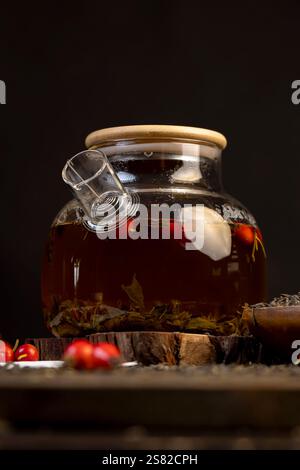 teapot with brewed tea with rose fruits, red rosehip fruits and hot green tea in a transparent teapot Stock Photo