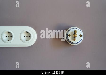 Retro style light switch and socket on dark pink wall Stock Photo