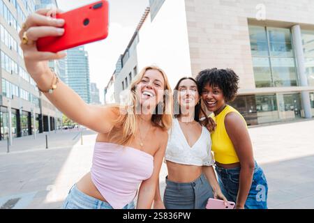 Joyful Group of Three Women Taking a Fun Selfie Together with a Cellphone, Radiating Happiness and Friendship in a Bright Outdoor Setting, Capturing a Memorable Moment Full of Laughter and Excitement. High quality photo Stock Photo