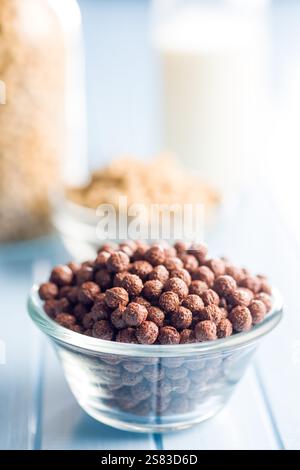 Breakfast cereal chocolate balls in bowl on a blue table. Stock Photo