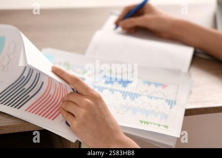 Young woman writing down something while working with documents in office. Closeup Stock Photo