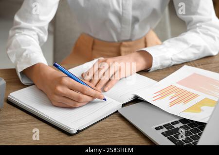 Young businesswoman writing down something while working with documents in office. Closeup Stock Photo