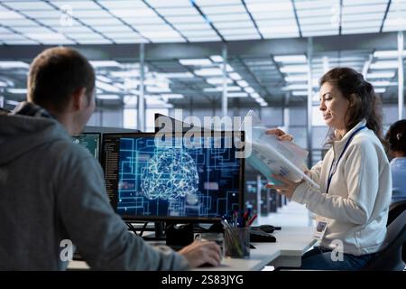 Manager looking over paperwork in machine learning server farm to ensure compliance with industry standards and regulatory requirements. Supervisor overseeing data center security protocols Stock Photo