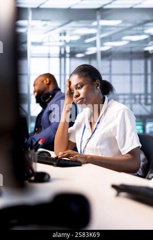 Data center technician feeling headache from stress while using programming languages on PC. Fatigued server farm worker debugging and optimizing code, feeling overworked Stock Photo