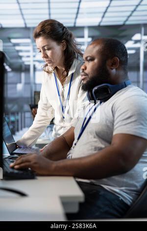 Teamworking colleagues updating AI systems, writing intricate binary code scripts on PC and laptop. Team of engineers using programming to upgrade artificial intelligence simulation model Stock Photo