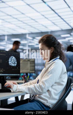 System administrator in AI server room doing system analysis, coding supercomputers. Artificial intelligence specialist working in high tech facility housing advanced storage infrastructure Stock Photo