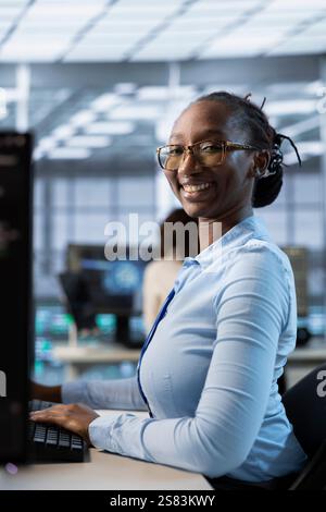 Portrait of smiling technician in data center coordinating deployment of server architecture, improving data processing speed. Happy woman in server hub configuring and testing equipment Stock Photo