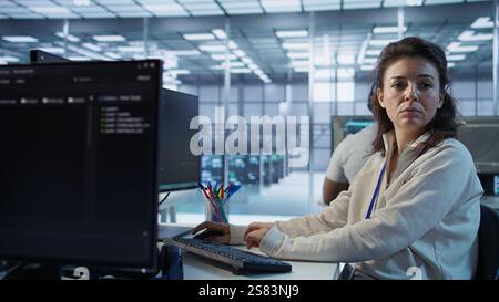 Portrait of smiling technician using PC to do maintenance on artificial intelligence neural networks. Cheerful admin using AI system aiding in processing and transmitting information, camera B Stock Photo