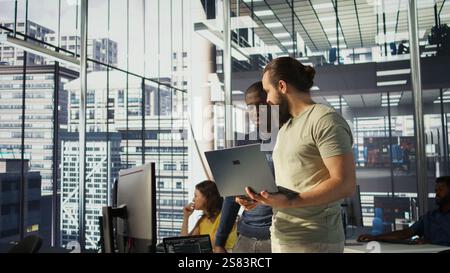 Programmer and colleague conducting experiments and tests to optimize machine learning models for performance and accuracy. IT staff members in office analyzing and interpreting complex data, camera B Stock Photo