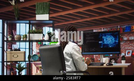Teleworking programmer using computer for artificial intelligence computing through self learning algorithms. Remote worker working with AI deep neural networks on desktop PC, camera A wide angle shot Stock Photo
