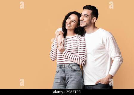 Nice Offer. Millennial Arab Couple Embracing And Looking Aside At Copy Space Stock Photo