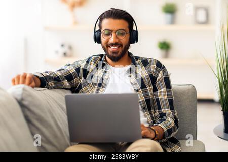 Relaxed middle-eastern guy watching movie online, using laptop Stock Photo