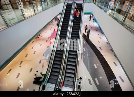 Century Place, ShenZhen, China - January 20, 2025 : High-angle view of two escalators in a modern shopping mall.  People are sparsely distributed, sug Stock Photo