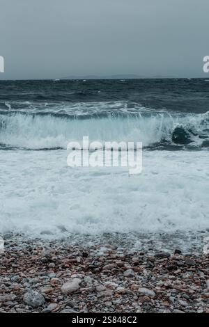 Choppy ocean waves under a cloudy sky with a solitary rock visible, in ...