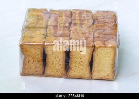 A packet of crispy rusk toast, dry cake biscuits on a light wooden background. Stock Photo