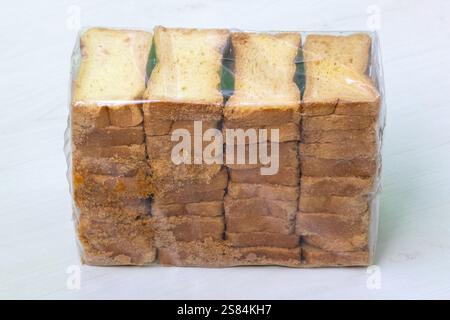 A packet of crispy rusk toast, dry cake biscuits are kept on a light wooden backdrop. Stock Photo