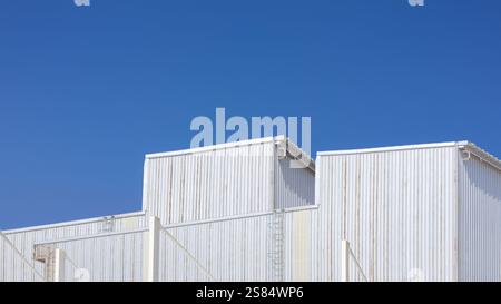Factory industry, Warehouse Construction in Geometric Modern Design, Architecture Building with Aluminium Facade on Blue Sky Background, Backdrop Wall Stock Photo