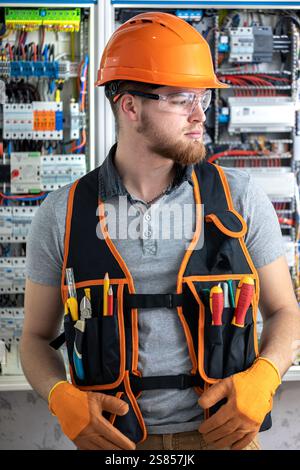 Electrician man in overalls works in the switchboard. Portrait of an electrician in overalls. Stock Photo