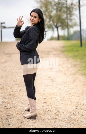 Young businesswoman making ok sign while standing on a path in a park Stock Photo