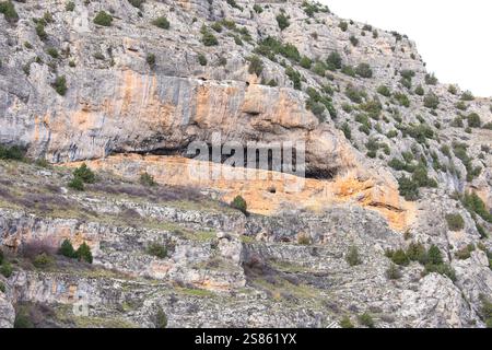 Caves on the rocky wall of the gorge of Guadalaviar river in Albarracin town, Spain Stock Photo