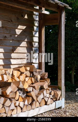 A large pile of logs drying in the sunshine in a cotswold garden. Stock Photo