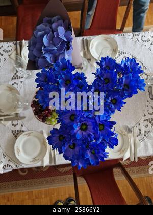 Blue flowers on a beautifully set dining table with a white linen lablecloth, simple, cozy atmosphere, a gathering, special occasion Stock Photo