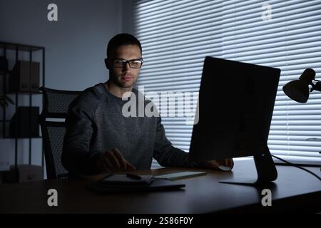 Programmer working on computer indoors at night Stock Photo