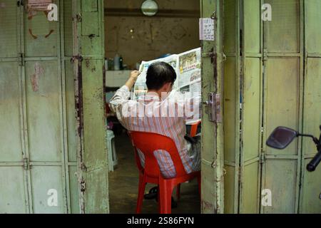 GEORGE TOWN, MALAYSIA - JANUARY 24, 2024: Chinese man reading a newspaper in one of the houses in traditional clan jetties on Penang island Stock Photo