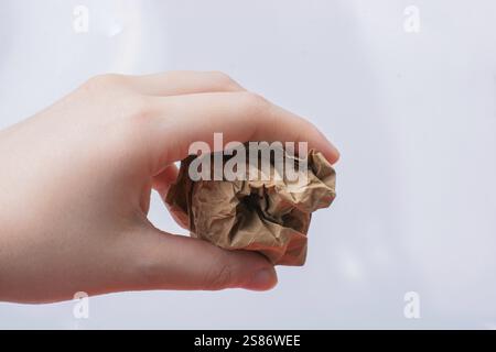 Female hand holds a crumpled paper ball on a white background Stock Photo