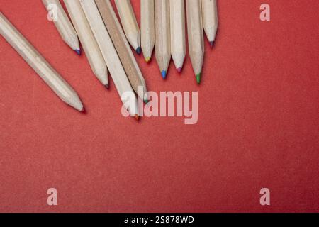 Colored pencils on red background. Many different colored pencils Stock Photo