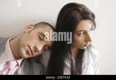 Young man and woman leaning against the wall, man is sleeping on woman's shoulder, Moscow, Russian Federation Stock Photo
