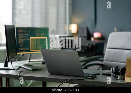 Background shot of professional programmers laptop placed on working desk equipped with several computers in office setting, copy space Stock Photo