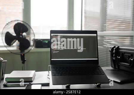 Background shot of laptop on support stand placed on professional programmers desk with various office stationery and devices at office workplace, copy space Stock Photo