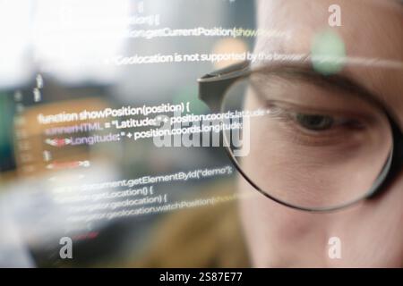 Extreme close up of male IT programmer wearing glasses looking at computer screen with lines of code, double exposure effect, copy space Stock Photo