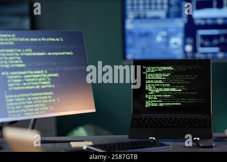 Background shot of laptop on support stand resting on professional programmers workstation with several computers at office workplace, copy space Stock Photo