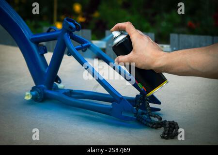 Spray Painting a Bicycle Frame Outdoors. Stock Photo