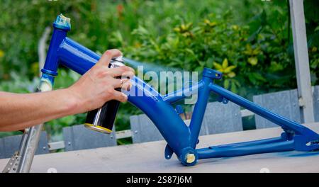 Spray Painting a Bicycle Frame Outdoors. Stock Photo