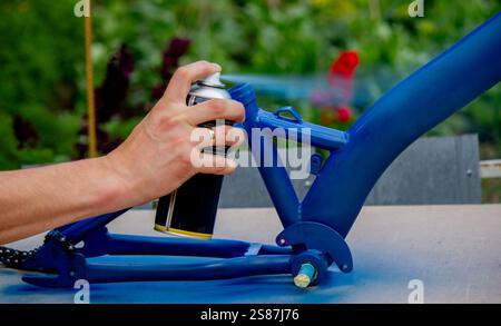Spray Painting a Bicycle Frame Outdoors. Stock Photo