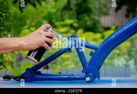 Spray Painting a Bicycle Frame Outdoors. Stock Photo