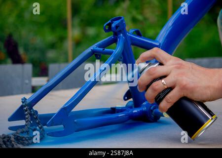 Spray Painting a Bicycle Frame Outdoors. Stock Photo