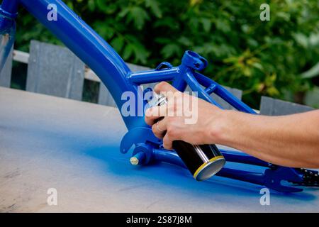 Spray Painting a Bicycle Frame Outdoors. Stock Photo