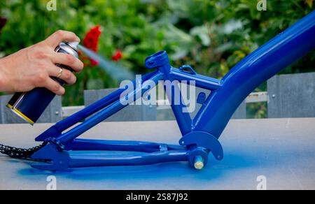 Spray Painting a Bicycle Frame Outdoors. Stock Photo