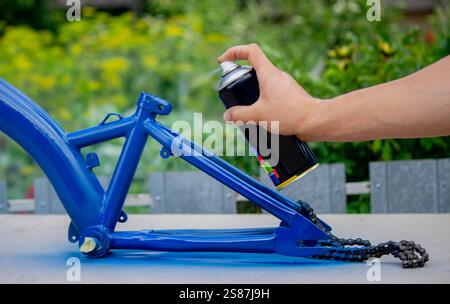 Spray Painting a Bicycle Frame Outdoors. Stock Photo