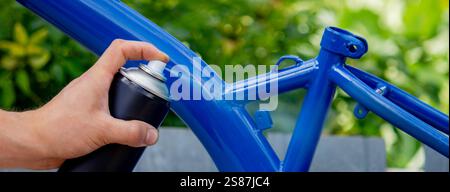Spray Painting a Bicycle Frame Outdoors. Stock Photo