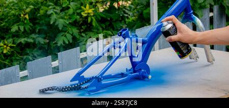 Spray Painting a Bicycle Frame Outdoors. Stock Photo