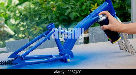 Spray Painting a Bicycle Frame Outdoors. Stock Photo