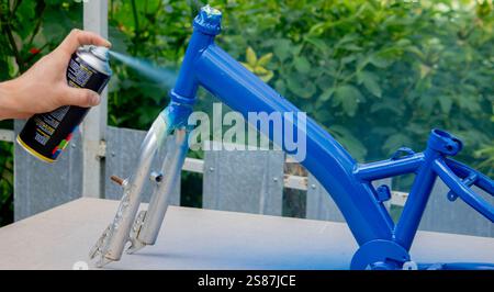 Spray Painting a Bicycle Frame Outdoors. Stock Photo
