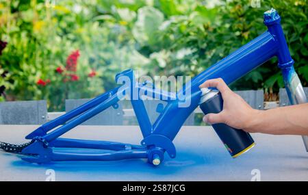 Spray Painting a Bicycle Frame Outdoors. Stock Photo